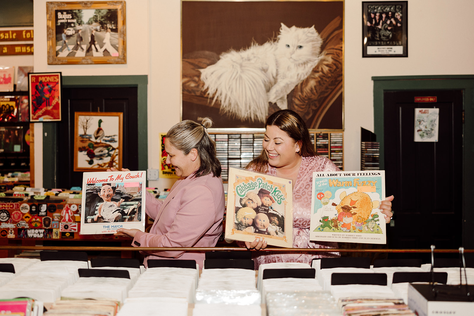 Women showing records to each other at a record shop during their city engagment session