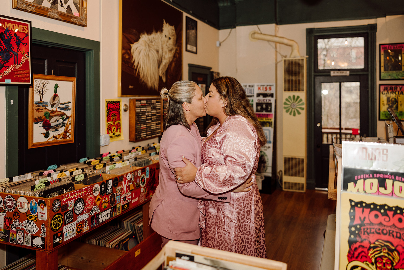 Women kissing at a record shop during their city engagment session
