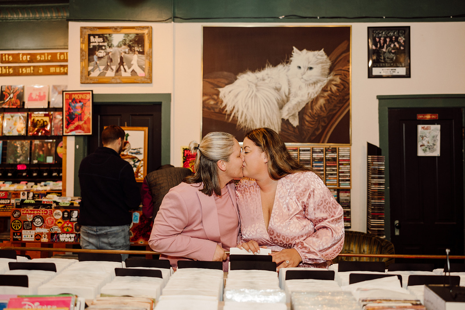 Women kissing at a record shop during their city engagment session