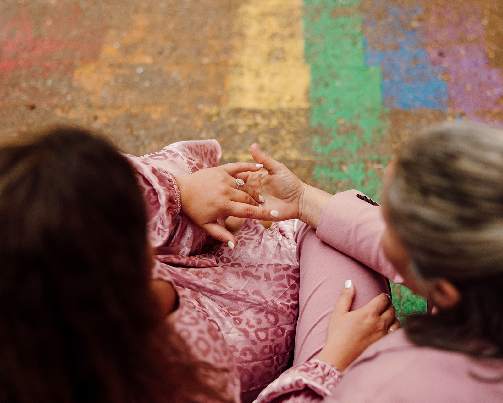 Women holding hands while sitting on rainbow stairs during their city engagment session