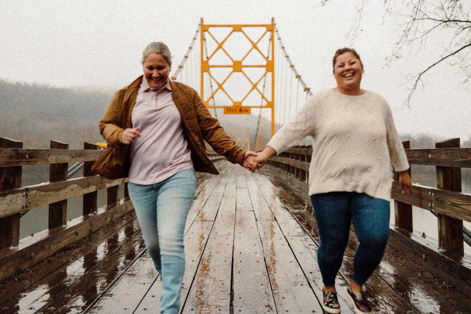Women holding hands while walking on a bridge