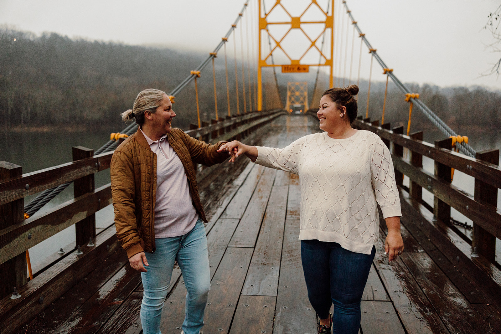 Women holding hands while walking on a bridge