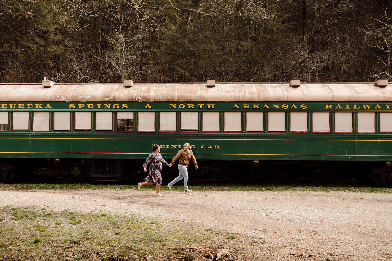 Women running next to a green train 