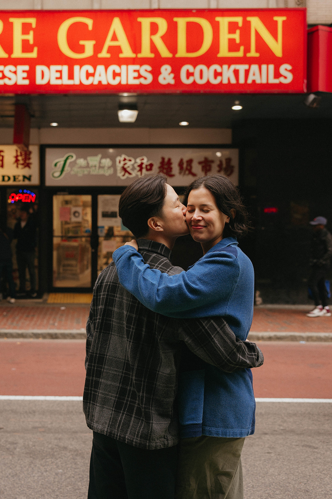 Soo Bin & Julie embrace in front of a bright red marquee in their iconic engagement session photos in Boston's Chinatown