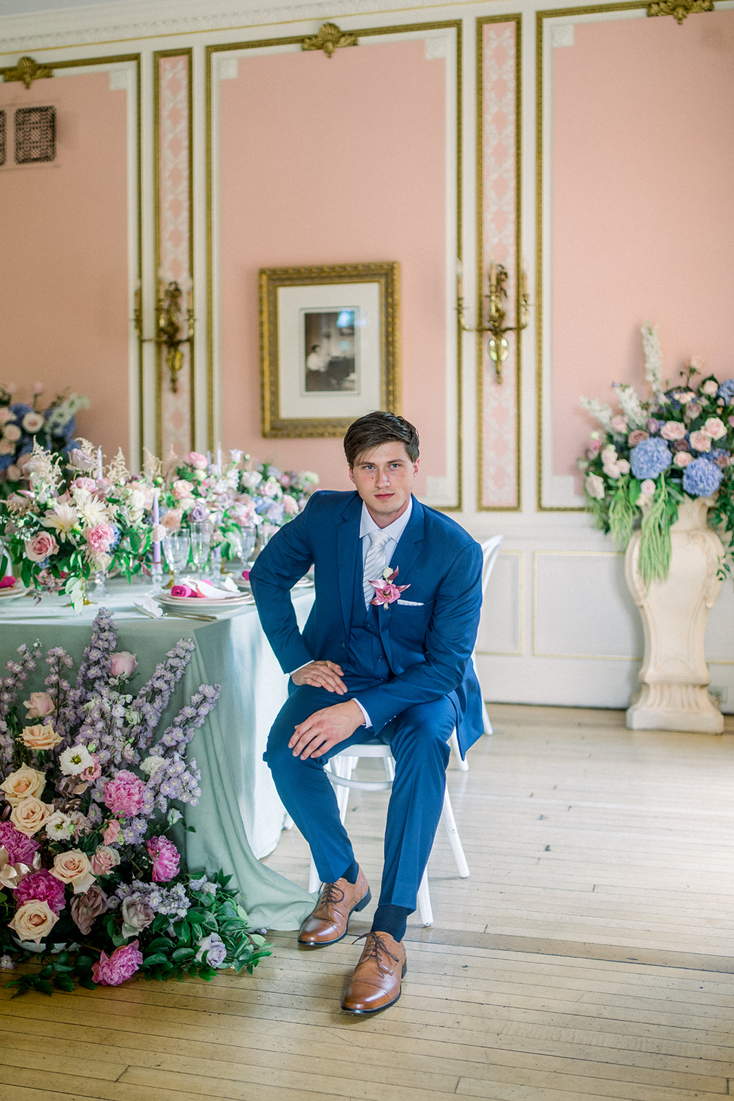 Groom in blue suit from  with a boutonniere, waiting in Cairnwood Estate's historic setting.