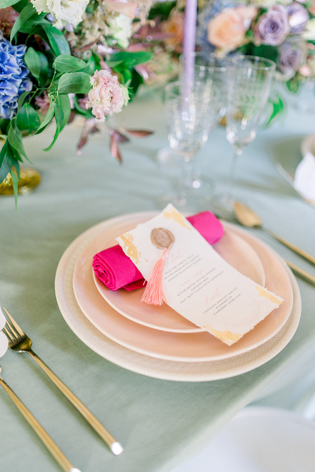  luxury destination weddin table setting featuring a pastel pink charger plate, gold cutlery, and an elegant invitation 
