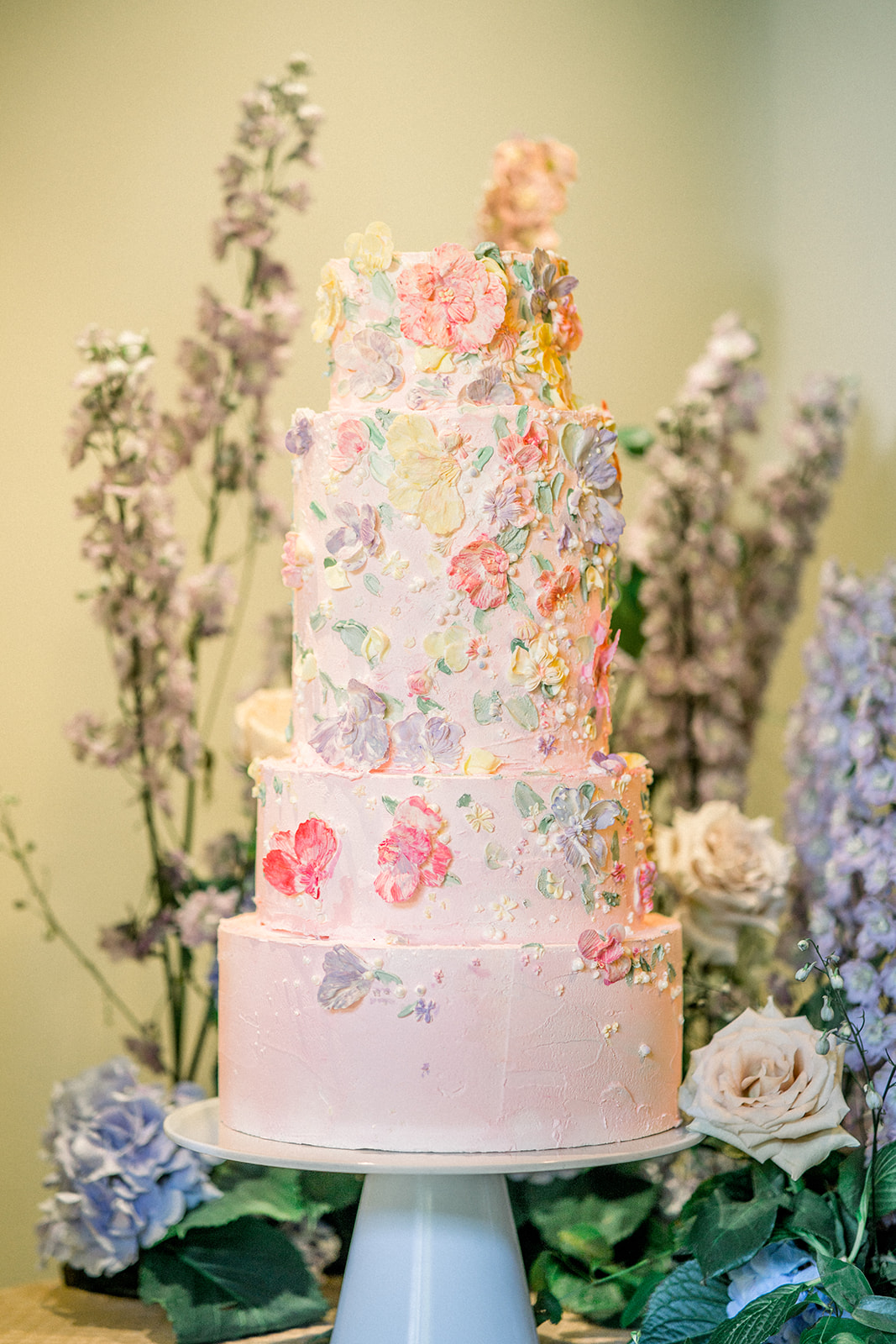 Opulent wedding cake with floral accents by Duchess Of Desserts, set against a backdrop of Cairnwood Estate's grandeur.