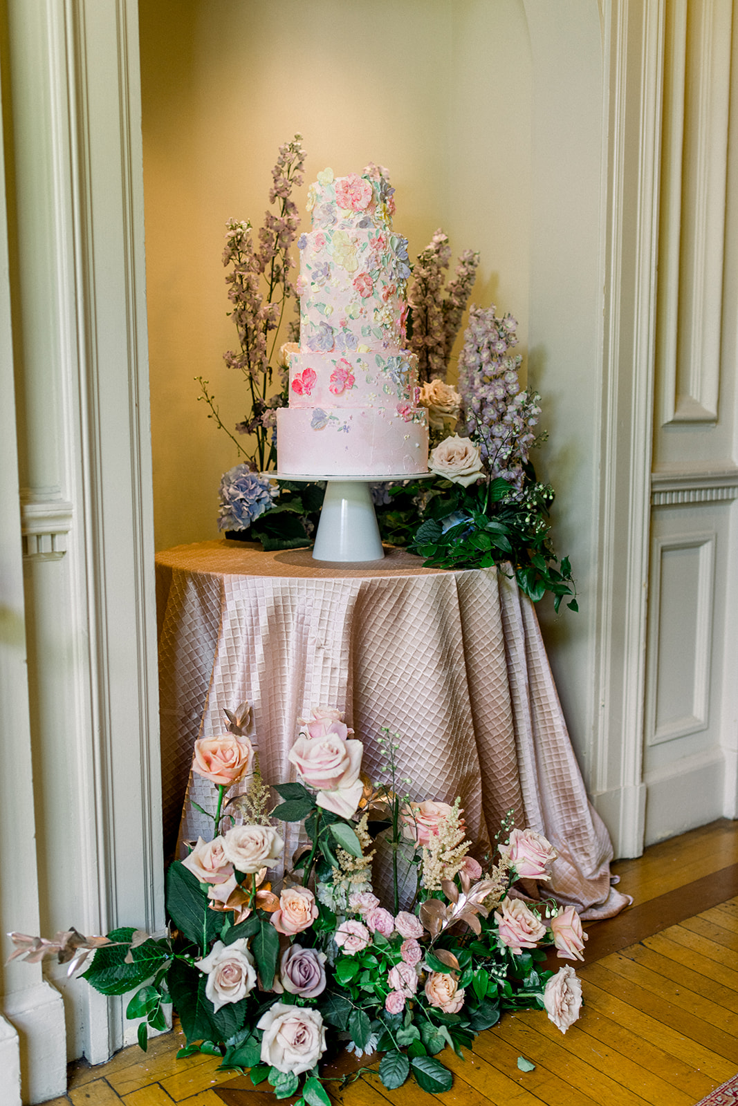 Opulent wedding cake with floral accents set against a backdrop of Cairnwood Estate's grandeur.