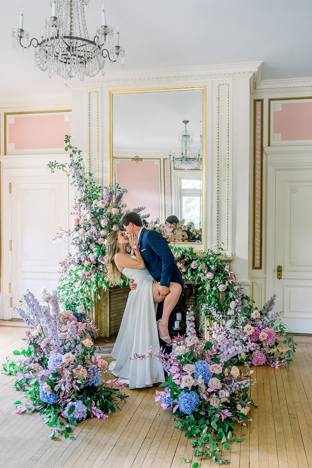 Romantic embrace of bride and groom amidst lush florals at a luxury Cairnwood Estate wedding.