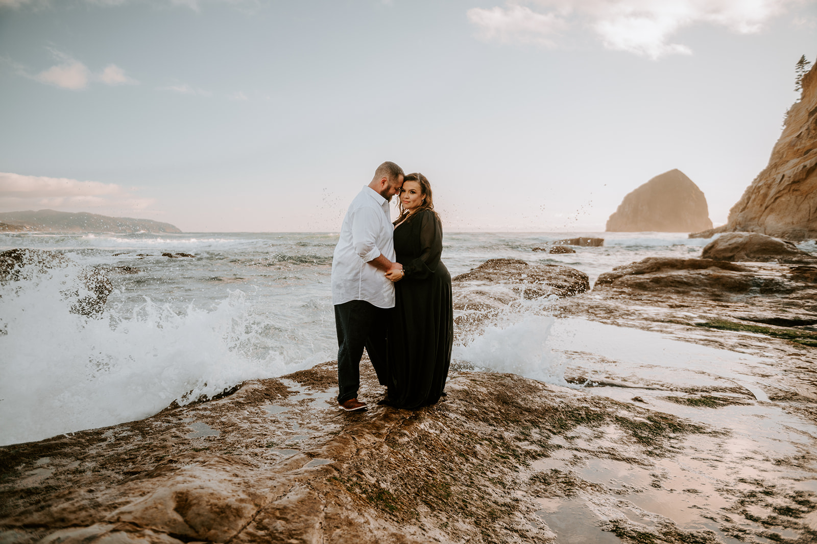 Couple embracing in front of waves on the Oregon Coast.