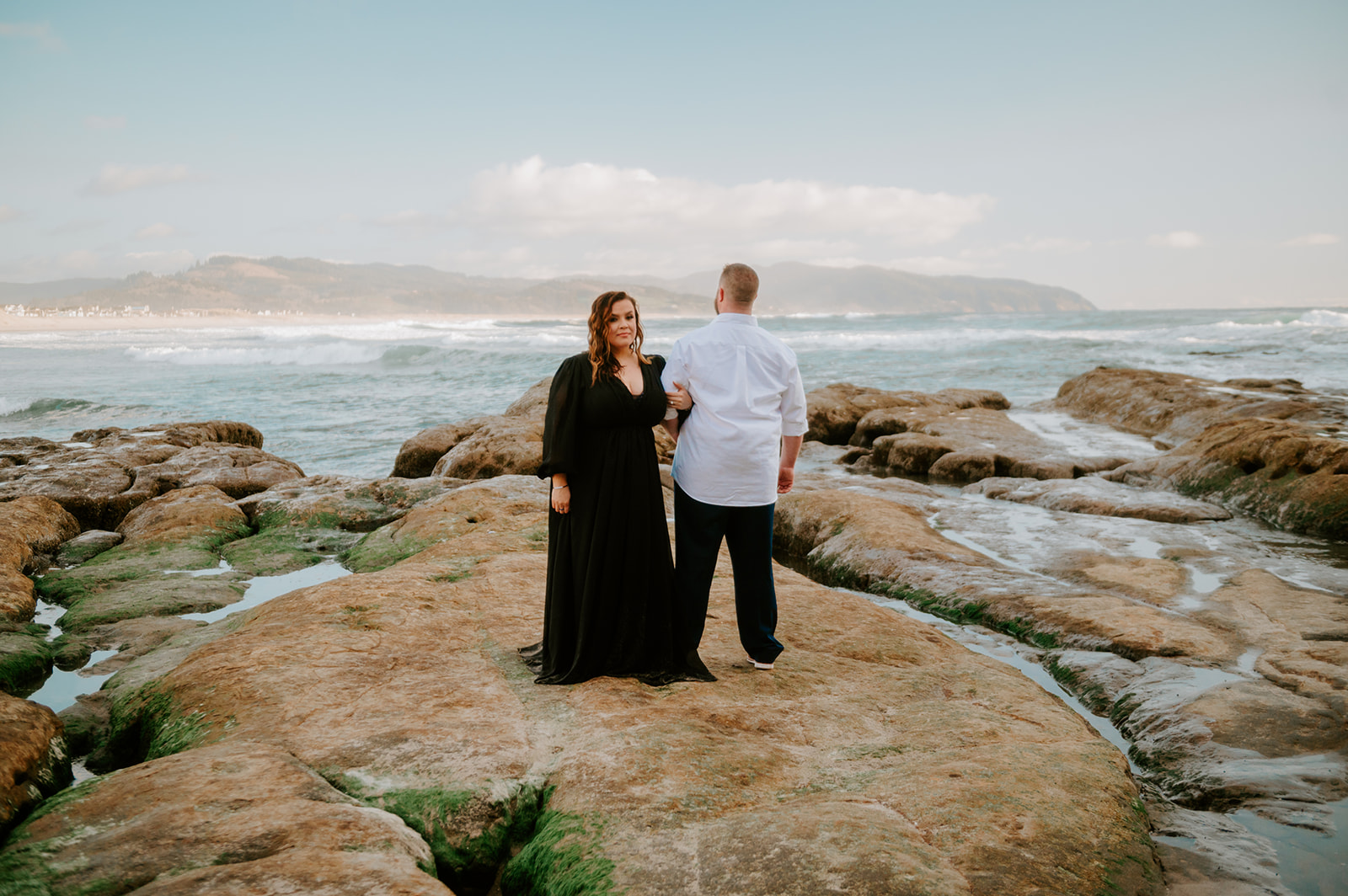 Couple posing on the rocks in the ocean on the oregon coast for engagement photos