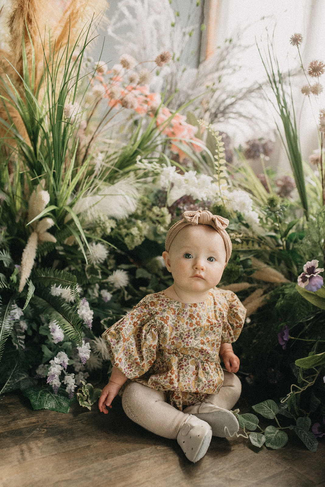 Cute little baby girl in the floral green garden