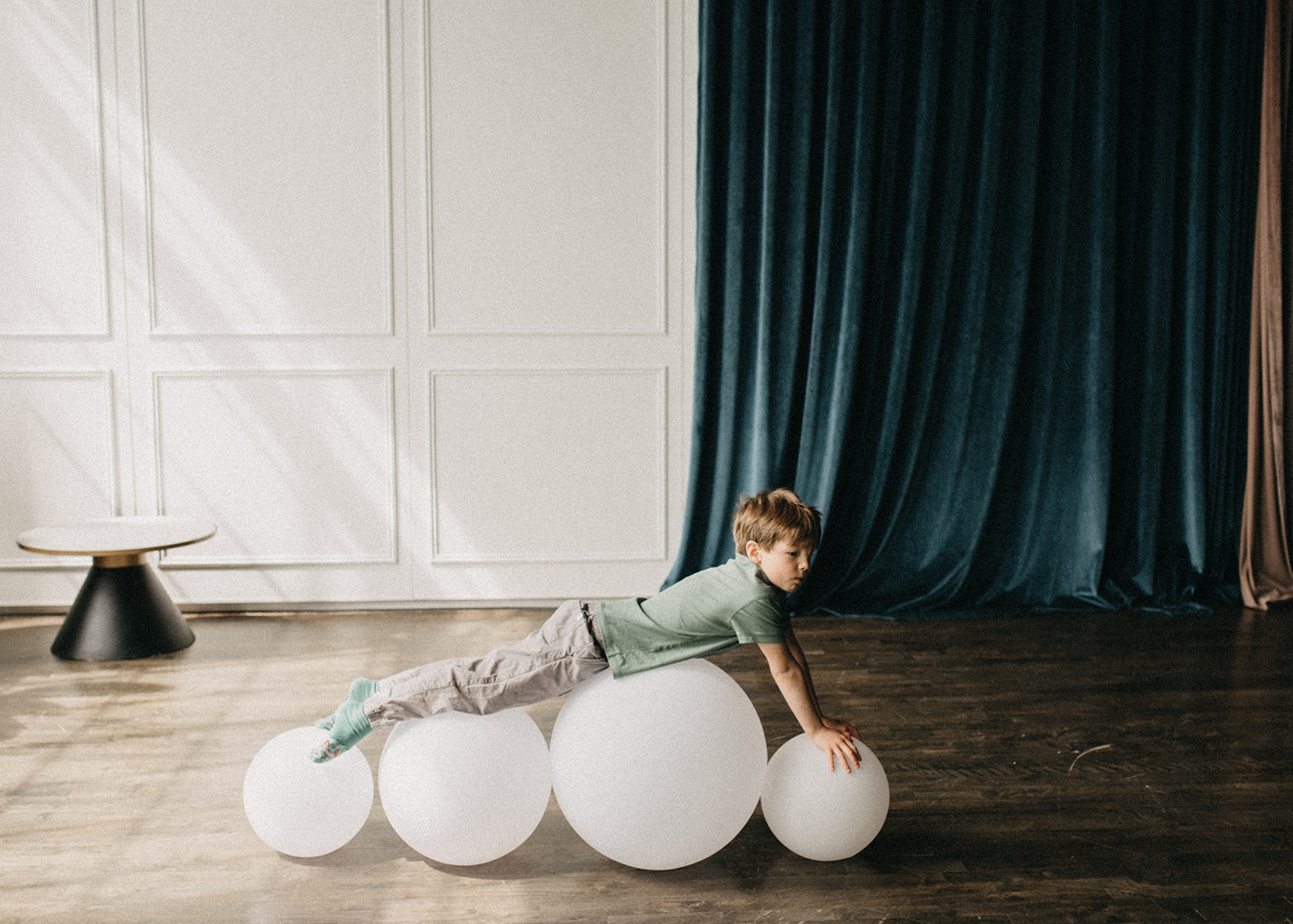A photo of a 6 years old boy going gymnastics routine on the white balls in a studio in Toronto