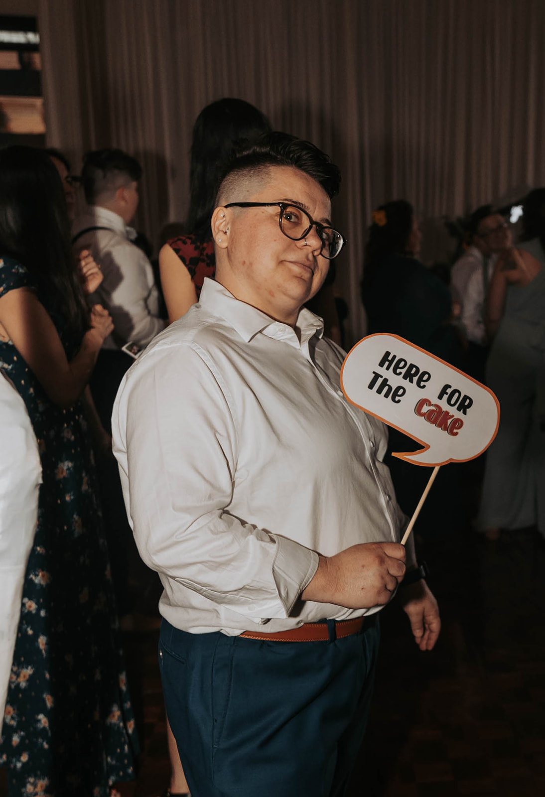A wedding guest holds a sign that says "I'm just here for the cake" 