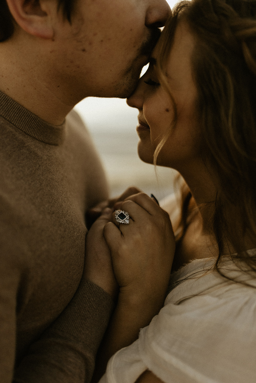 A man kissing his fiance's forehead while she closes her eyes and smiles