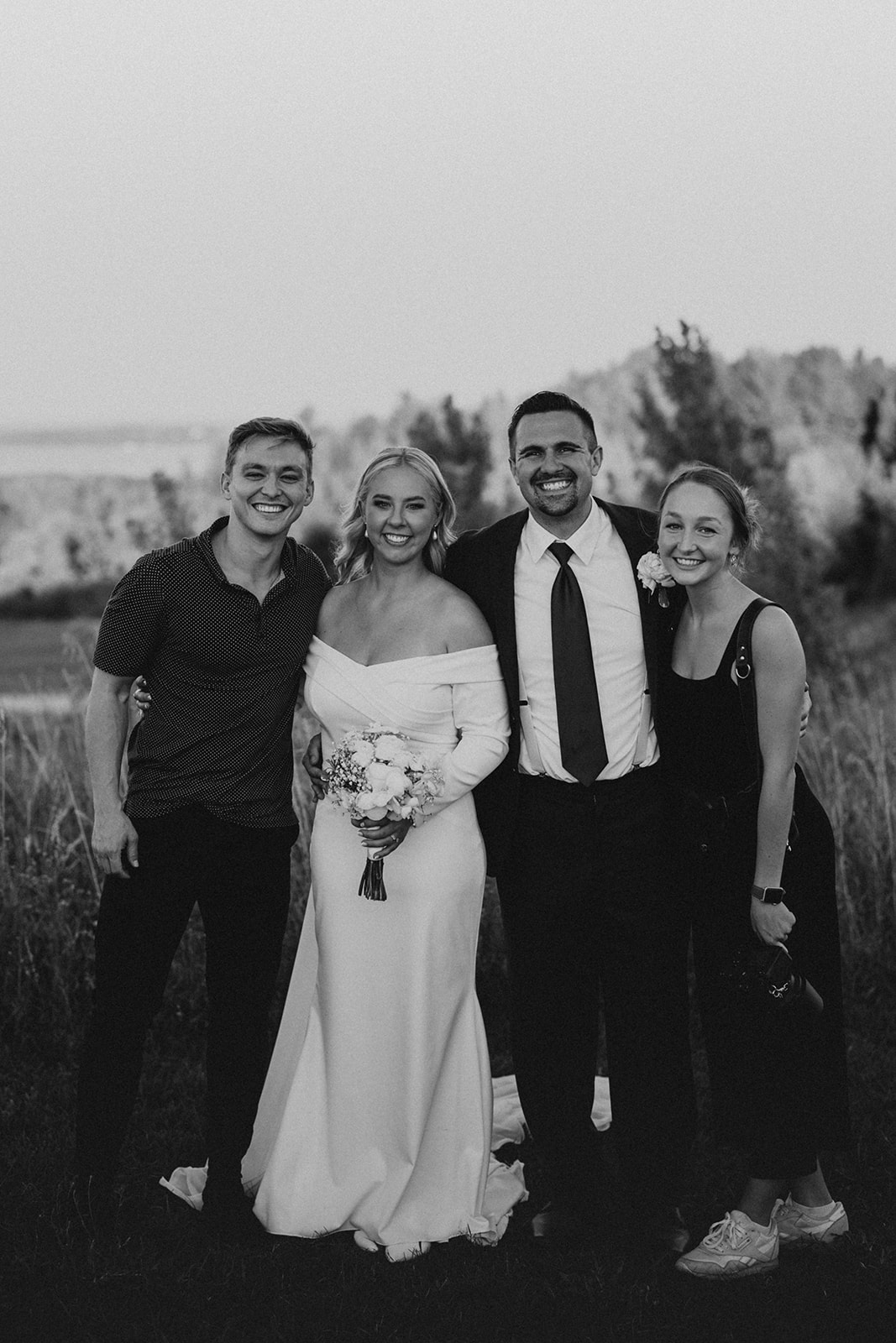 A photographer and videographer taking a photo with a bride and groom 