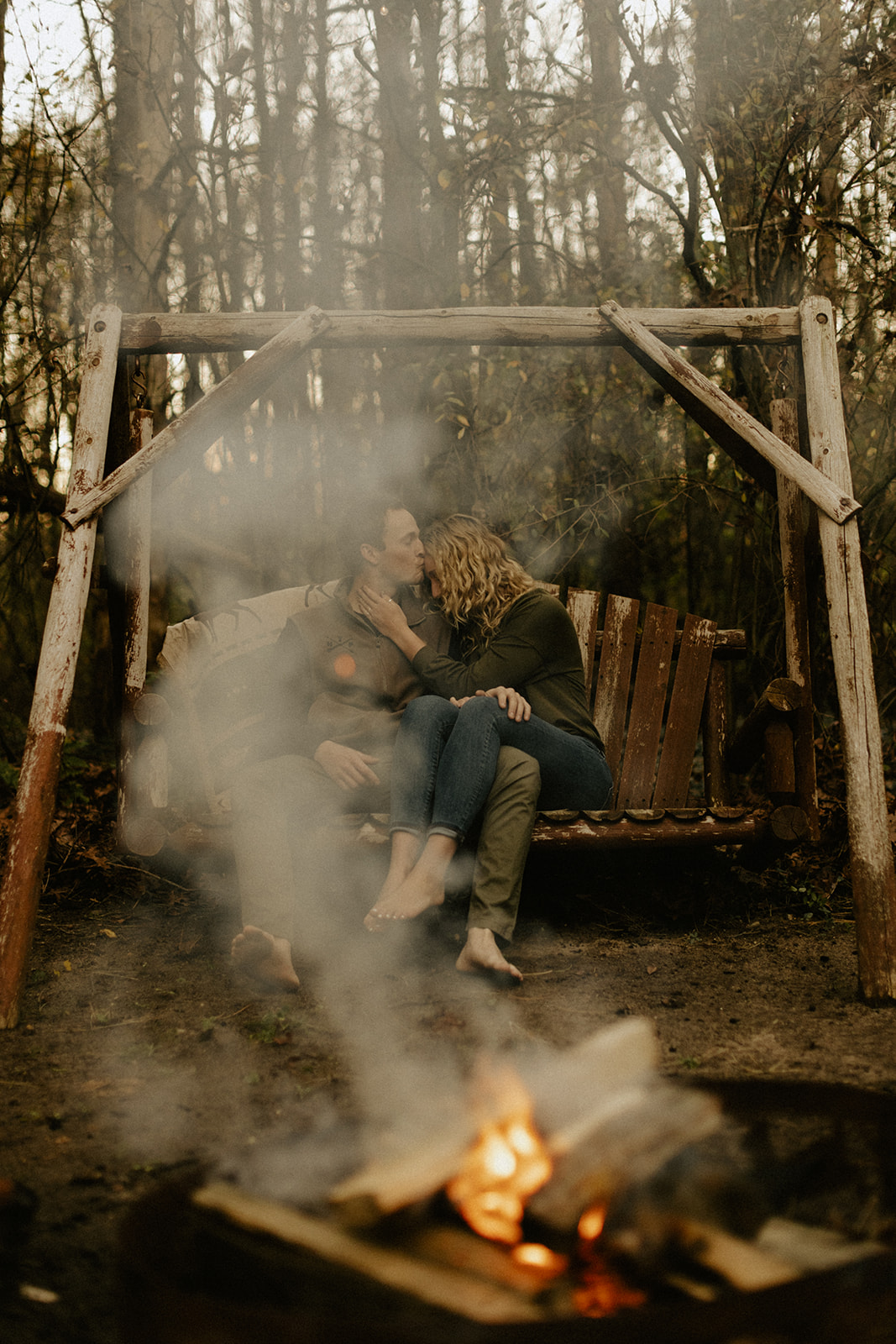 A couple sitting on a bench and cuddling in front of a campfire