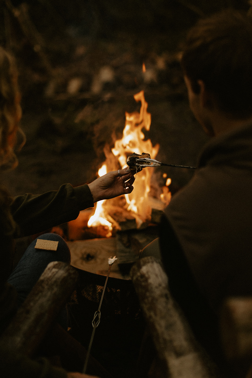 A couple making s'mores around a campfire together