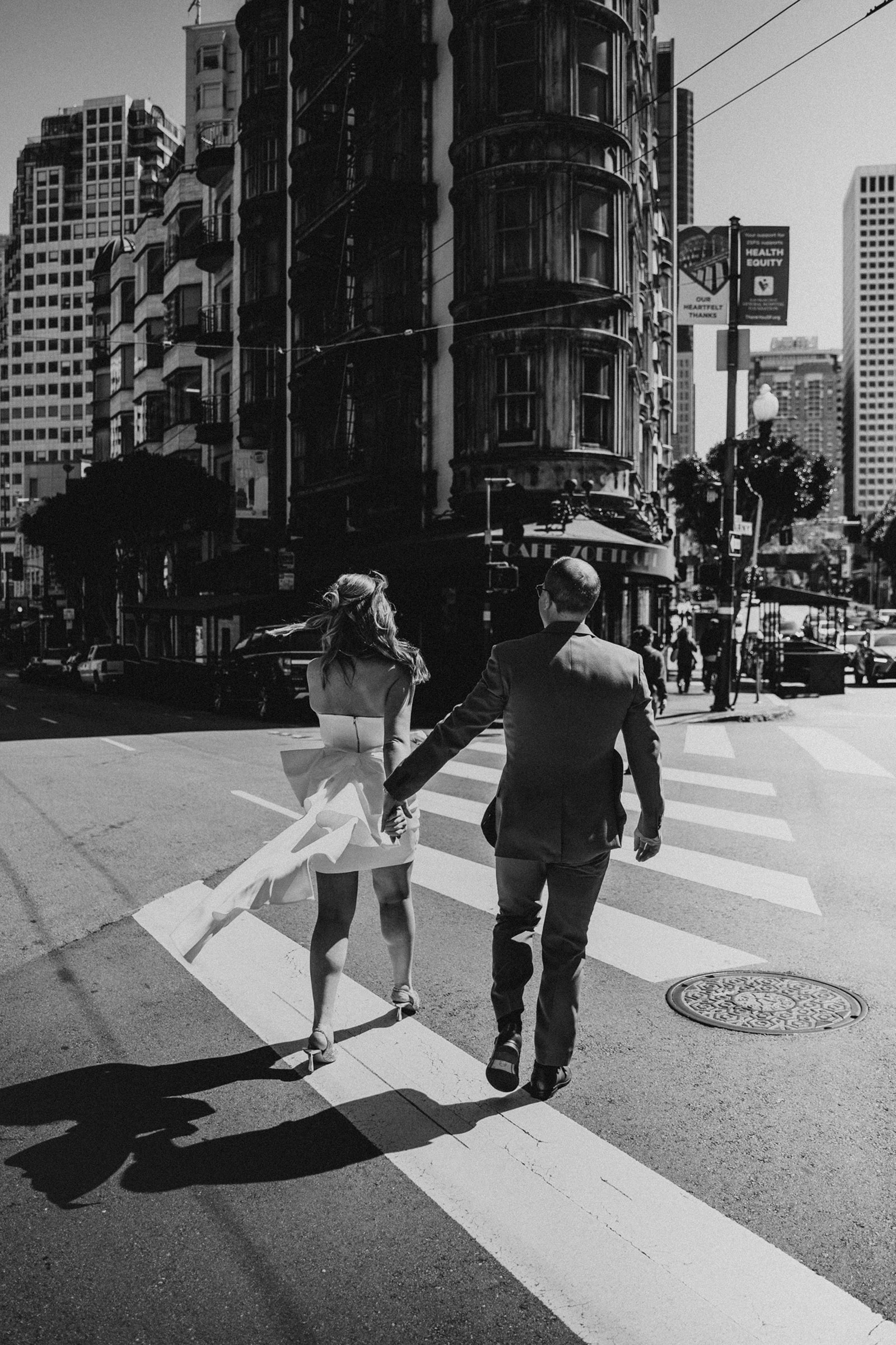couple crosses the street at the Sentinel Building in San Francisco