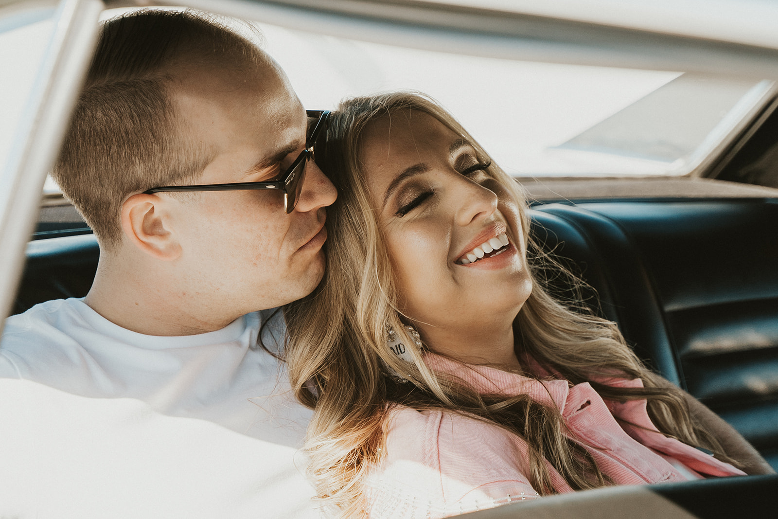 engaged couple sitting in backseat of Oldsmobile Cutlass Supreme smiling
