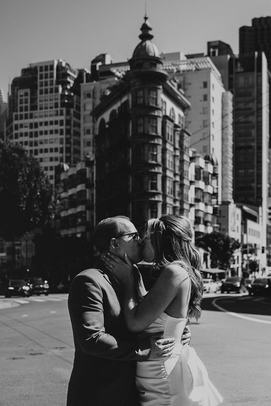 newly engaged couple kissing in front of the Sentinel Building in San Francisco