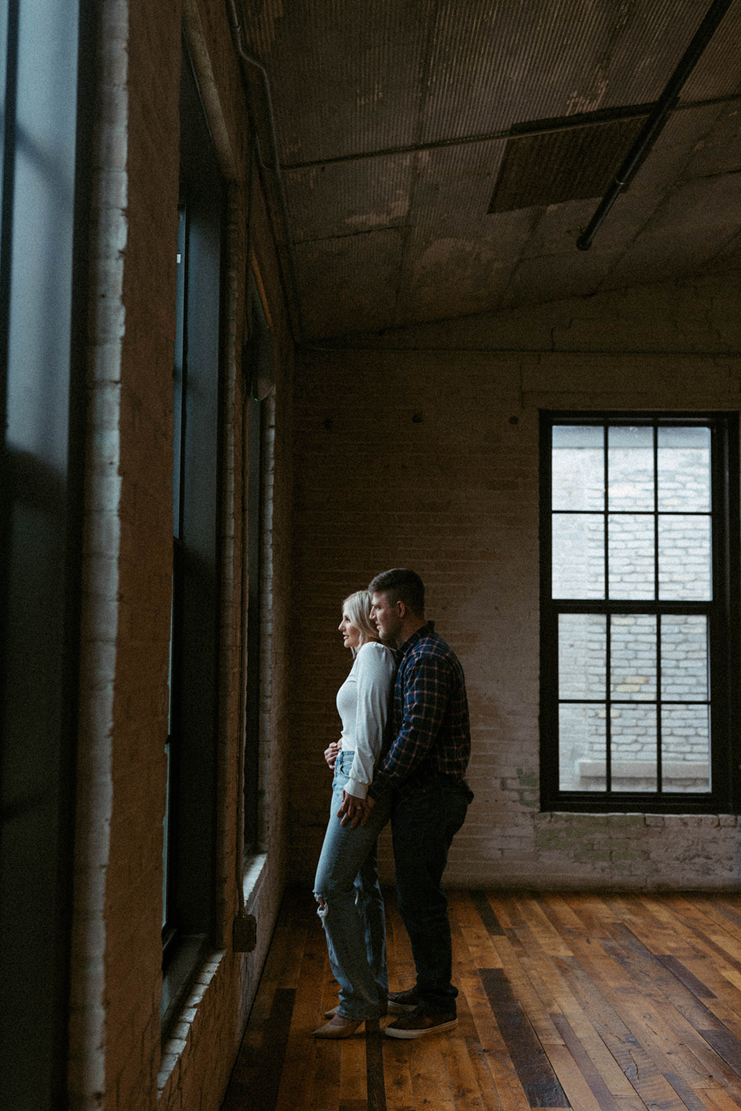 couple look out the window together during their journeyman distillery engagement