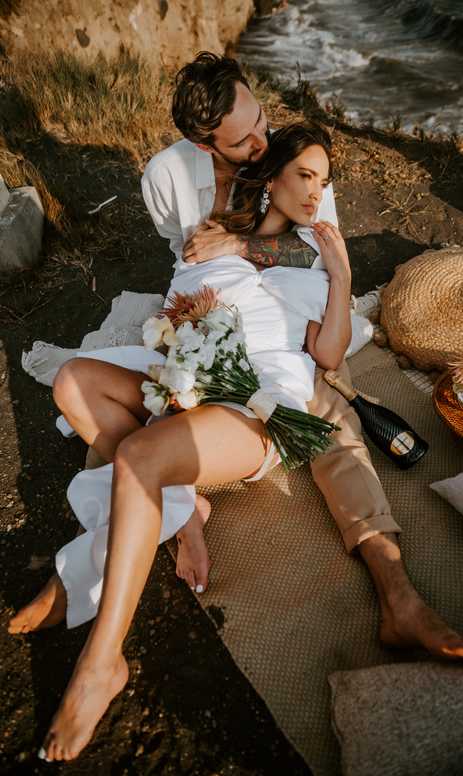 Bride laying on her husband wearing a short wedding dress holding a monochromatic bouquet