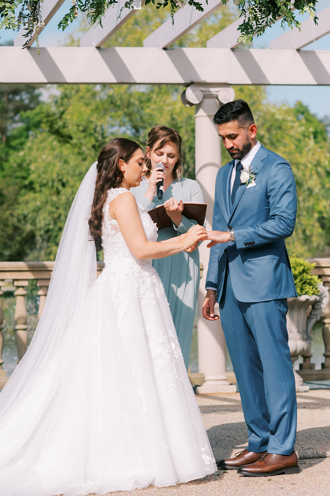 morais vineyard winery virginia bealeton wedding bride and groom putting rings on a line wedding dress blue suit gold 