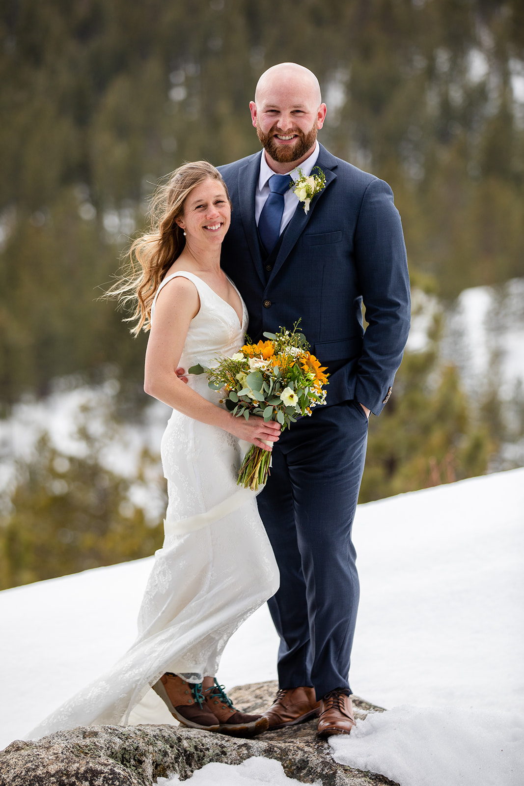 Wedding couple standing together with pine trees in the background